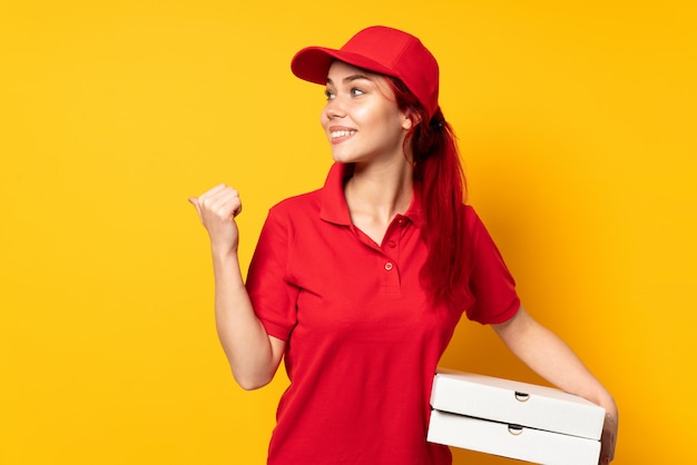 Pizza delivery woman holding a pizza pointing to the side to present a product
