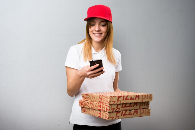 Pizza delivery woman talking to mobile on textured background