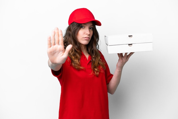 Foto donna di consegna della pizza con uniforme da lavoro che raccoglie scatole di pizza isolate su sfondo bianco facendo un gesto di arresto