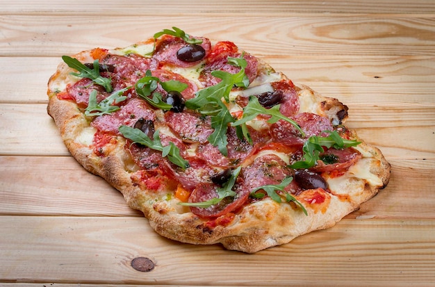 Pizza Diavolo met chorizo rucola jalapeno chili kalamata pesto Romeinse pizza rechthoekig op hout achtergrond