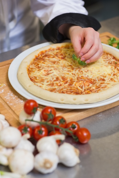 Pizza die met basilicumblad wordt versierd