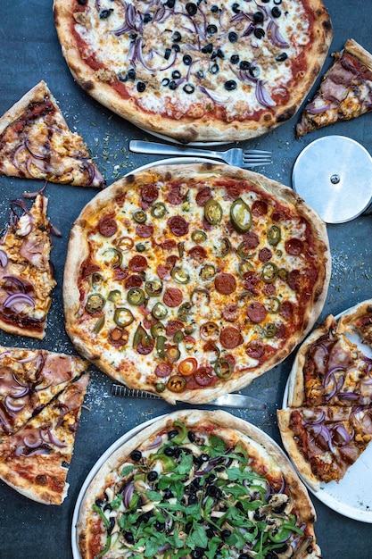 ピザディナー素朴なテーブルトップビューにさまざまな種類のイタリアのピザを平らに並べたクイックランチお祝い会議コンセプトの垂直写真
