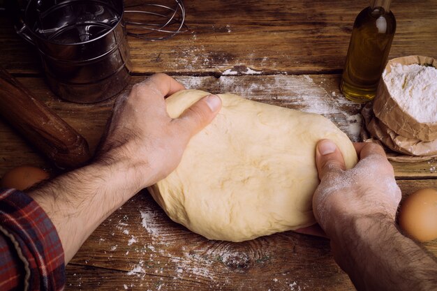 Pizza dough cooking in the home kitchen. Homemade dough for bread, pizza, pastries and rolls. Dough ingredients on a wooden rustic background