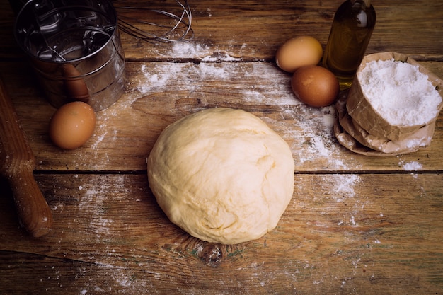 Pizza dough cooking in the home kitchen. Homemade dough for bread, pizza, pastries and rolls. Dough ingredients on a wooden rustic background