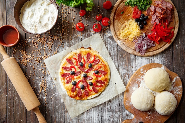 Pizza dough with ingredients on wood