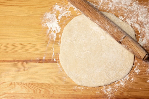 Pizza dough on wooden background Rollingpin and flour Selective focus top view