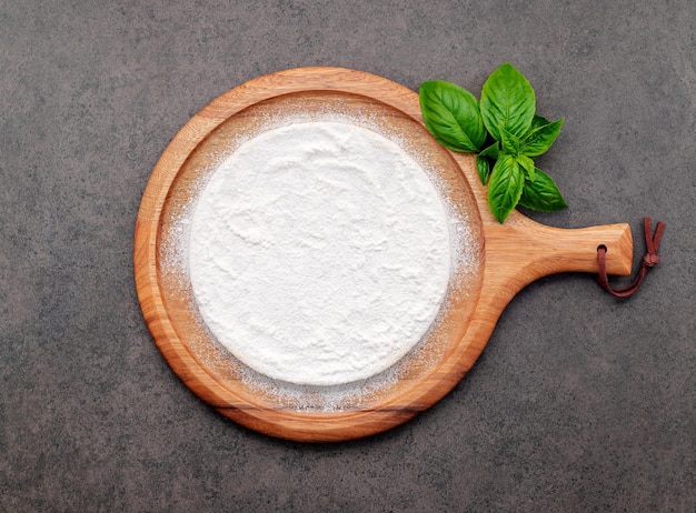 Pizza dough in wooden pizza platter set up on dark concrete Pizza tray on dark concrete background flat lay and copy space