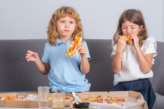 Pizza en kinderen snijden pizza in de hand van kinderen kinderen meisje en jongen eten smakelijke fastfoodpizza met che