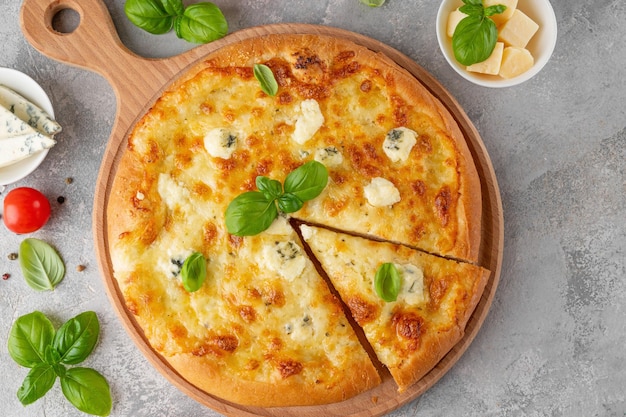 Pizza four cheeses with fresh basil on top on a wooden board on a gray concrete background Top view copy space