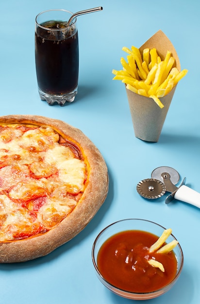 Foto pizza, patatine fritte e soda con ghiaccio su sfondo blu