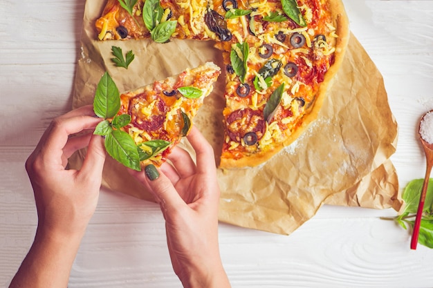 Pizza and hand close up over white background