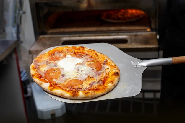 Pizza in de oven zetten bij de keuken van het restaurant.