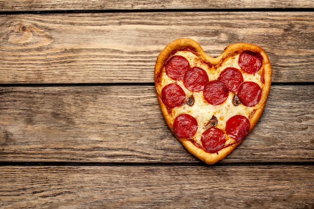 Pizza in de vorm van een hart op een houten tafel