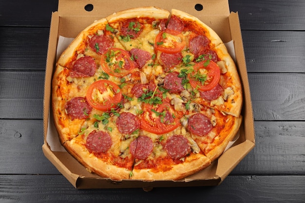 Pizza in een kartonnen doos close-up op een zwart bord