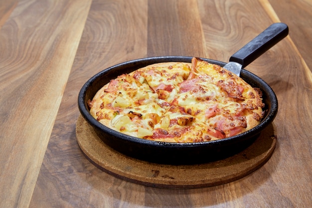 Pizza in snijplank op een houten tafel zijaanzicht.