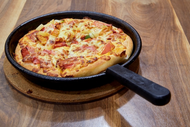 Pizza in snijplank op een houten tafel zijaanzicht.