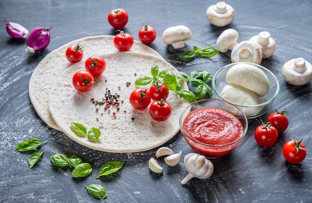 Pizza-ingrediënten op de donkere houten achtergrond