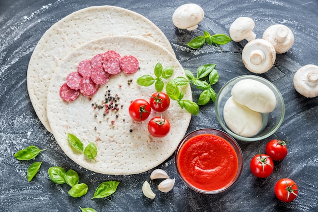 Pizza ingredients on the dark wooden background