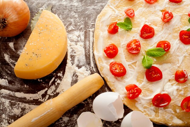 Pizza is in the process of cooking, cherry tomatoes are spread out on the dough