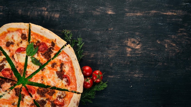 Pizza Italiaanse keuken Bovenaanzicht Op een zwarte houten achtergrond Kopieer de ruimte