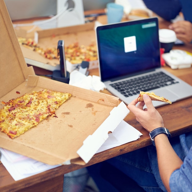 Pizza kantoor en werknemer handen op laptop scherm voor het programmeren van software en informatietechnologie Persoon of programmeur eten fastfood bij start-up bedrijf of baan met webontwikkeling op de computer