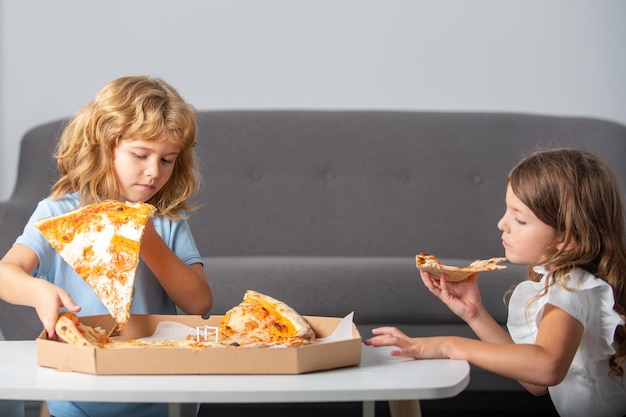ピザと子供たちは子供たちの手でピザをスライスします子供たちはチーズと一緒においしいファーストフードのピザを食べますリトルch