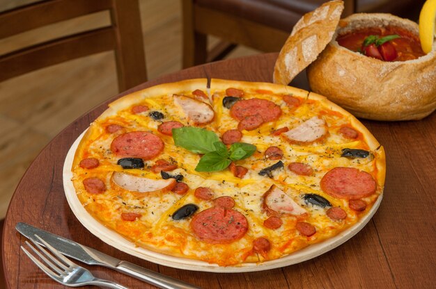 Pizza on the kitchen table with a fork and sauce