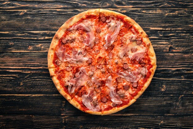 Pizza Lardon. Bacon, cherry tomatoes, sausage salami. On a wooden background. Top view.