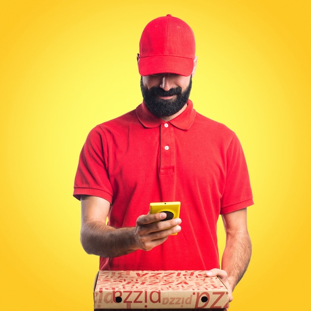 Pizza levering man met een mobiele telefoon op kleurrijke achtergrond