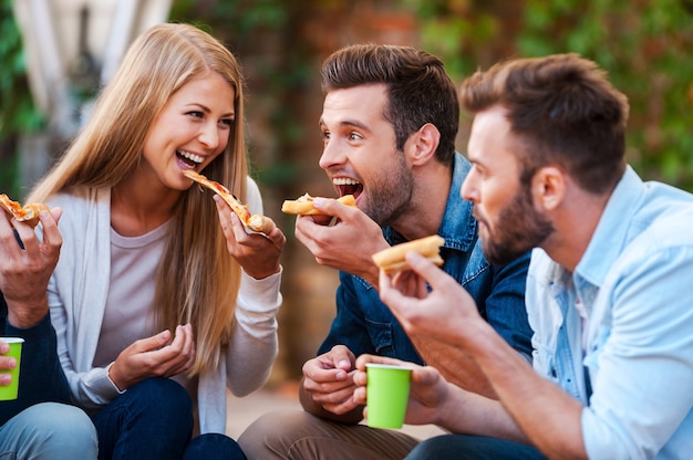 Foto amanti della pizza. gruppo di giovani giocosi che mangiano pizza divertendosi insieme