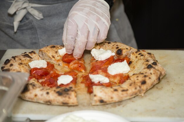 Pizza maker who prepares a delicious pizza with cheese and cherry tomatoes