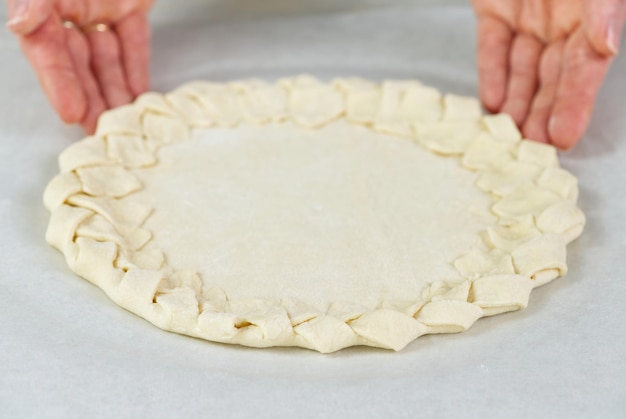 Процесс приготовления пиццы Вид сверху на основу из теста для пиццы Домашняя выпечка пиццы с плетеной корочкой для пирога крупным планом