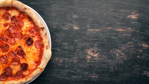 Pizza margarita con salsicce e salsa di pomodoro su uno sfondo di legno vista dall'alto spazio libero per il testo