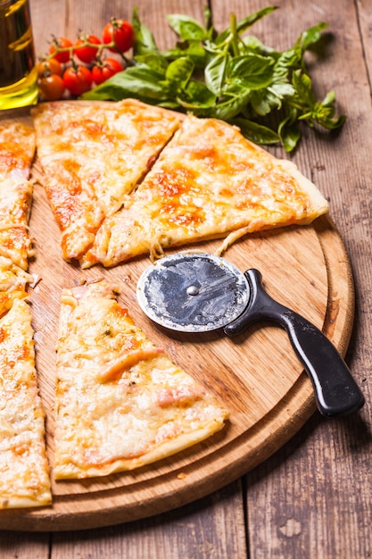 Pizza Margarita on the wooden board and pizza cutter