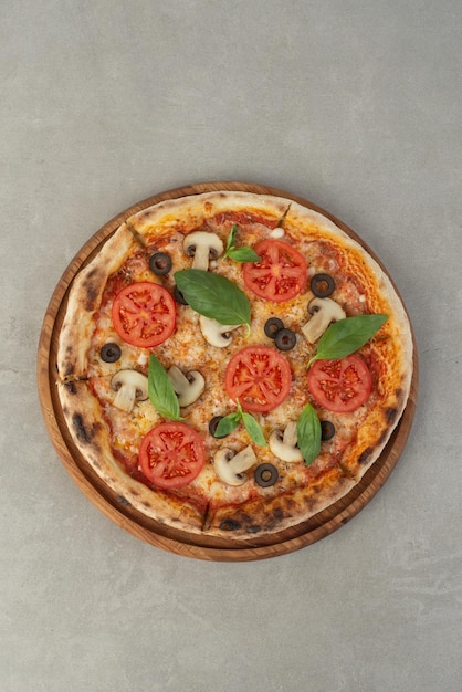 Pizza margherita met tomaten en champignons op een grijze achtergrond bovenaanzicht