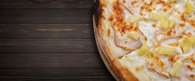 Pizza met ananas van vleesham op een houten rond bord op een houten achtergrond