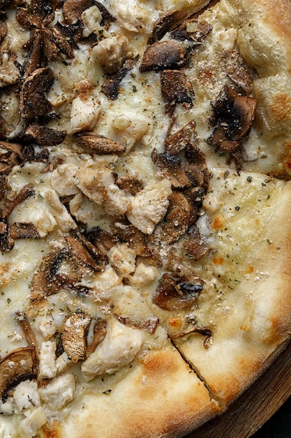 Pizza met champignons en kip op een houten plank verticaal