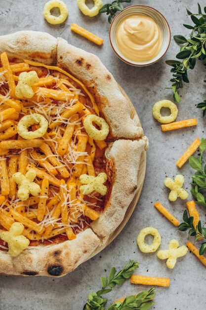 Foto pizza met cheetos-chips en saus op een grijze achtergrond