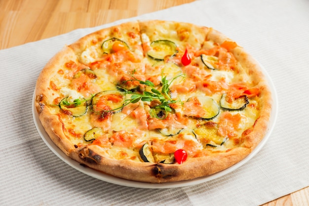 Pizza met courgette, rode vis en kaas, op een witte plaat