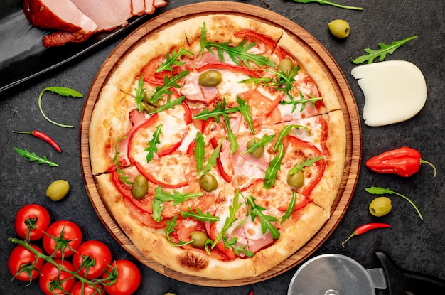 pizza met ham tomaten kaas op een stenen achtergrond