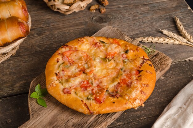 Pizza met kaas en tomaten op een houten achtergrond met ingrediënten, fast food