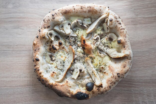 Foto pizza met kip en paddenstoelen room saus op houten oppervlak gebakken korsten in de napolitaanse oven