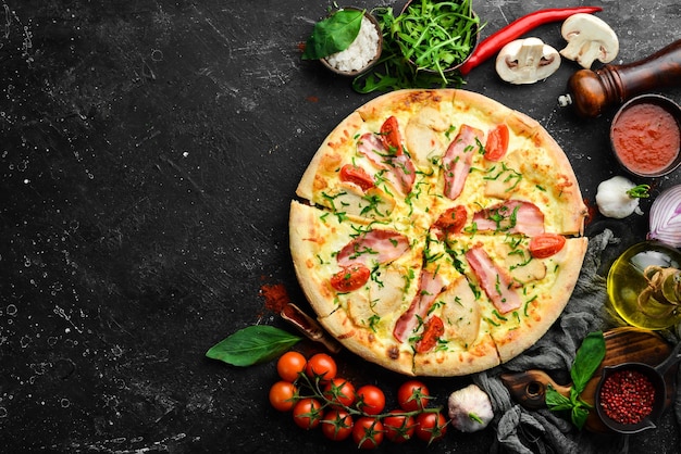 Pizza met kippenspek en kersentomaten Italiaanse keuken op een zwarte achtergrond