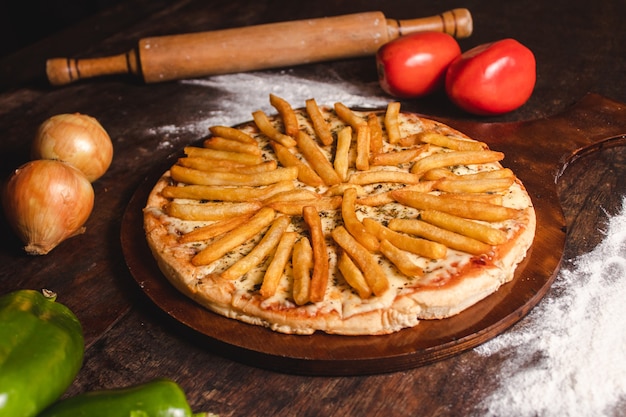 Pizza met mozzarella en friet op een houten tafel.