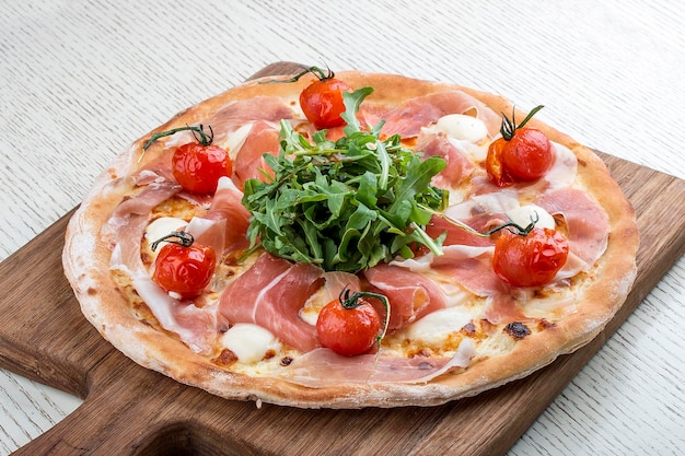 Pizza met Parmaham mozzarella en cherrytomaatjes op een houten plank