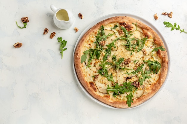 Pizza met peer, blauwe kaas, walnoot en rucola op lichte achtergrond. banner, menu, receptplaats voor tekst, bovenaanzicht