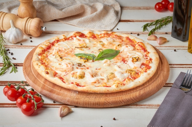 Pizza met plakjes, saus en kruiden, houten wit