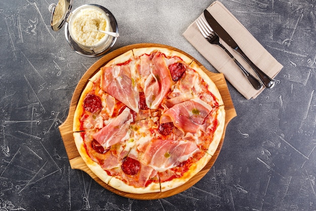 Pizza met salami en prosciutto op een houten bord