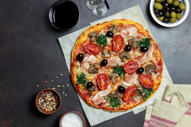 Pizza met spek, champignons, tomaten, kaas en olijven. Italiaans eten.