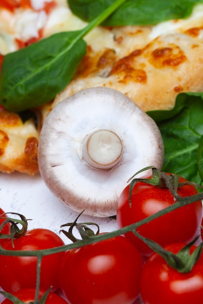 Foto pizza met spinazie, kersen, tomaten en gorgonzola kaas op een lichte achtergrond